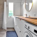 Badezimmer mit Dusche, Waschmaschine und Holz-Arbeitsplatte.