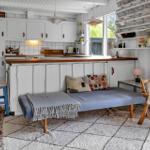 Küche mit Essbereich und Schlafsofa. Holzoberfläche und weiße Schränke.