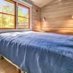 Ein Bett mit blauer Bettwäsche vor einem Fenster mit Waldblick.