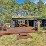 Holzhütte mit grünem Dach und großer Terrasse im Wald