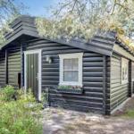 Holzhaus mit grünem Dach und Fensterbank mit Blumen.