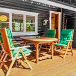 Terrasse mit Holztisch und grünen Stühlen vor einem Holzhaus.