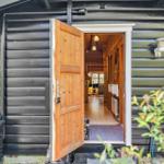 Holztür öffnet den Blick in das Innere des Hauses mit Holzboden und Fenster.