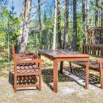 Holztisch und -bänke im Wald. Hintergrund: Holzstapel und Wäscheständer.