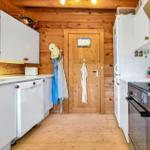 Küche mit weißen Schränken, Holzwand und Tür mit Haken.