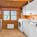 Küche mit Waschmaschine und Spülmaschine, Holzwände und Fenster mit Blick auf den Garten.