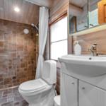 Badezimmer mit Toilette, Waschbecken und Dusche mit Steinwand.