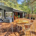 Holzterrasse mit Tisch und Stühlen vor einem Holzhaus im Wald