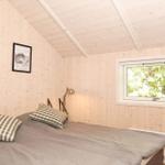 Schlafzimmer mit Holzwand, Bett und Fenster mit Blick auf Bäume.