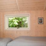 Schlafzimmer mit Holzwand, Fenster und Bett