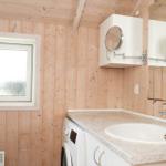 Badezimmer mit Waschmaschine, Waschtisch und Spiegelschrank an Holzwand