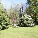 Garten mit Liegestuhl, Sträuchern und Bäumen. Hintergrund zeigt Teil eines Gebäudes.