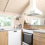 Küche mit Holzwand, Spüle, Herd und Dunstabzug.