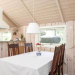 Esszimmer mit Holzwand, Tisch und Stühlen. Fenster und Küchenbereich sichtbar.