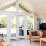 Wohnbereich mit Sitzgelegenheiten, Fernseher und großem Fenster zum Garten.