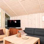 Wohnzimmer mit Sofa, Sessel, Couchtisch und Fernseher an Holzwand.