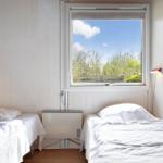 Zwei Betten mit weißen Bettwäsche, Fenster mit Blick auf Bäume und Himmel.