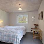 Schlafzimmer mit Bett, Fenster, Stuhl und Wandschrank. Holzwand und Decke.