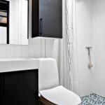 Bad mit Waschbecken, Toilette und Dusche mit Mosaikboden.