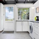 Küche mit Waschmaschine, Fenster und Tür zum Außenbereich.