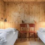 Zimmer mit zwei Betten, Holzwand und zwei Stühlen