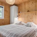 Schlafzimmer mit Holzwänden, Bett, Fenster und Schrank.