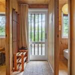 Hölzerner Flur mit Schlafzimmer und Bad. Tür führt auf Balkon mit Blick auf Wald.