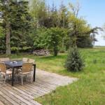 Holzterrasse mit Tisch und Stühlen im Grünen.