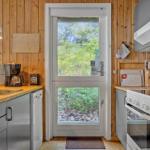 Küche mit Holzwand, Fenster zur Natur und Küchengeräten.