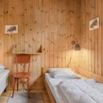 Zwei Betten in einem Raum mit Holzwandverkleidung und Fenster.