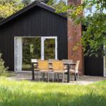 Schwarzes Holzhaus mit Terrasse und Sitzgruppe im Grünen