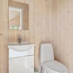 Badezimmer mit Toilette und Waschbecken an Holzwand