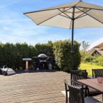 Terrasse mit Sonnenschirm, Grill und Esstisch mit Stühlen.