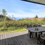Terrasse mit Tisch und Stühlen, Blick auf Wald und Meer.