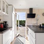 Küche mit weißen Schränken, schwarzer Arbeitsplatte und Blick auf die Terrasse.