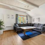 Wohnzimmer mit grauem Sofa, Holzboden und Dachschrägen.