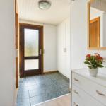 Eingangsbereich mit Holztür, Schrank und Schminktisch mit Spiegel.