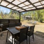 Terrasse mit Tisch, Stühlen, Grill und Blick in den Wald.