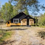 Ein gelbes Haus mit schwarzem Dach steht im Wald. Der Eingang ist mit Stufen versehen.