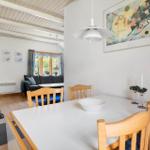 Esszimmer mit Tisch und Stühlen. Im Hintergrund Wohnbereich mit Sofa und Fenster.