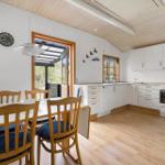 Küche und Essbereich mit Holzboden, weißen Schränken und Tisch mit Stühlen.