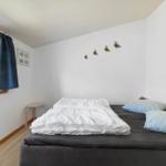 Schlafzimmer mit Bett, Fenster und Wanddekoration.