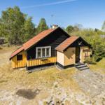 Holzhaus mit rotem Dach, gelben und schwarzen Wänden, Eingangstreppe und Garten.