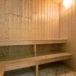 Sauna mit Holzwand und Sitzbänken auf Fliesenboden