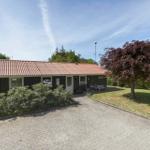 Einhaus mit Terrasse, Garten und gepflastertem Weg. Ein Baum mit roten Blättern steht daneben.