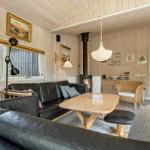 Wohnzimmer mit Holzwand, Sofa, Tisch und Kaminofen. Durchgang zur Küche.