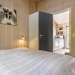 Schlafzimmer mit Bett, Wandbild und Stuhl. Küche im Hintergrund sichtbar.