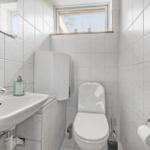 Bathroom with toilet, sink, and small window.