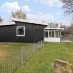 Black wooden house with white windows and terrace in the garden.