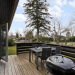 Deck with table, chairs, and grill. View of lawn and trees.